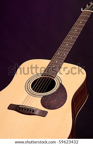 An acoustic guitar isolated against a black background in the vertical format.