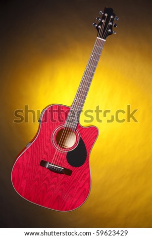 A red acoustic guitar isolated against a spotlight yellow background in the vertical format.