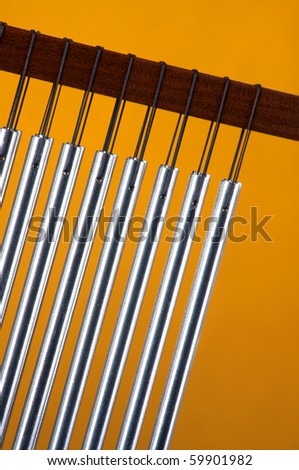 A set of wind bar chimes u close isolated on a gold yellow background in the vertical format with copy space.