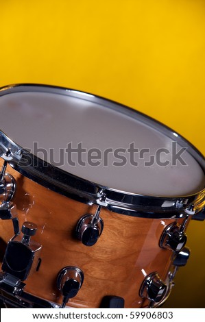 A brown  wood  snare drum isolated  on  a  yellow or gold background in the vertical format with copy space.