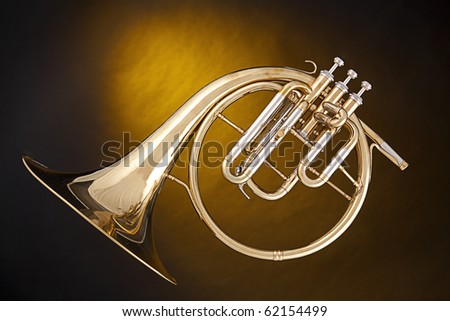 An antique French horn or peckhorn isolated against a spotlight yellow background with copy space.