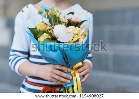 bouquet for first beloved teacher on first of September. Flowers for the last bell. day of knowledge. beginning of the school year. first-graders in a school uniform on the background of school