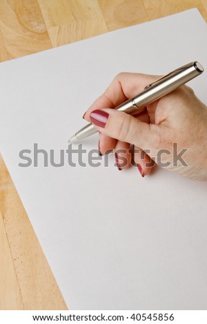 Woman\'s hand with pen in position to write on blank white paper with room to add text