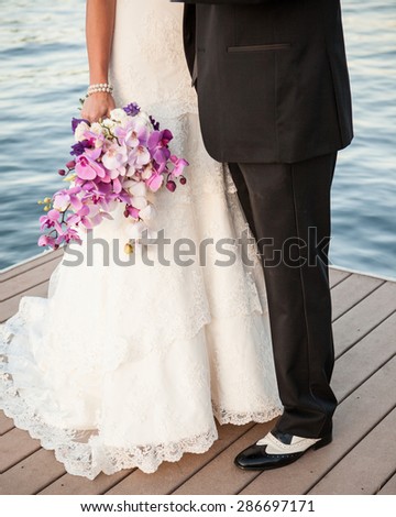 Bride & Groom purple bouquet, black and white spats on the lake dock