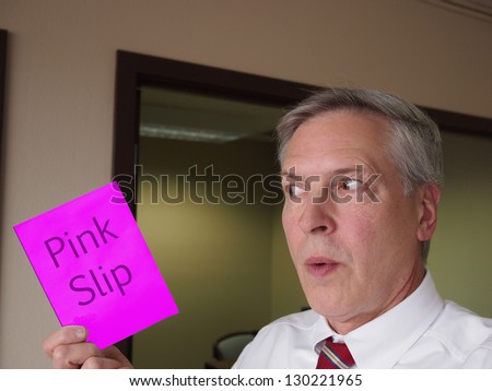Business man receives his notice of termination by way of the traditional pink slip.