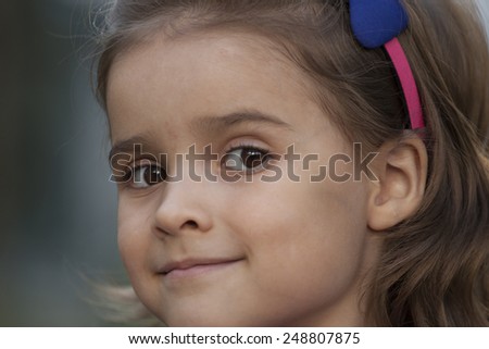 Sweet little girl outdoors with curly hair in the wind