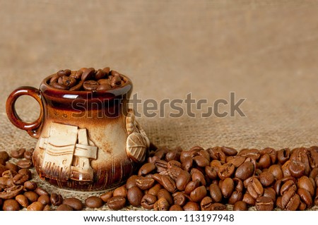Clay coffee cup with beans on the sack background, shallow depth of field
