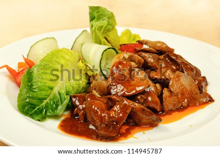 Roasted liver with sauce, lettuce and cucumber on dish in the restaurant