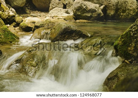 mountain fast flowing river stream of water in the rocks with moss