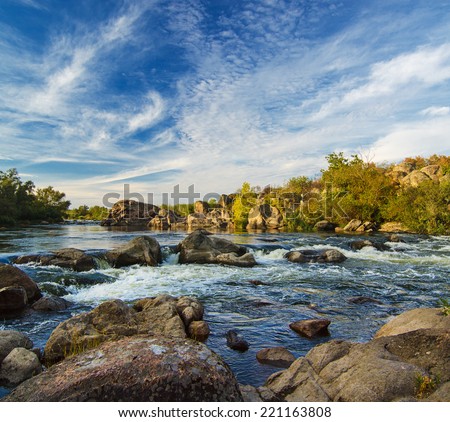 Mountain fast flowing river stream of water in the rocks with blue sky Mountain fast flowing river stream of water in the rocks with blue sky