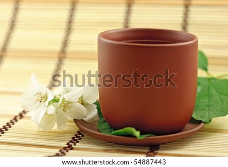 Clay cup with green tea and jasmin flowers