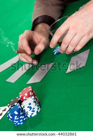 hands of the player's blackjack with a glass of whiskey and a cigar on the table with chips and cards