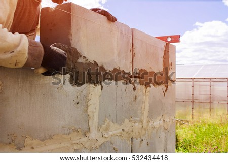 Bright sunny day, builder puts a wall of blocks. construction work.