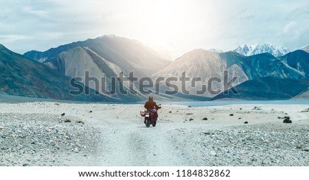 Tourist riding an adventure big bike motorcycle on tuff and bumpy road on rock mountain in clear beautiful lightning to explore the world, with copy space