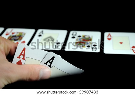 hand holding two aces cards and board with five cards isolated on black