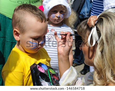 KALININGRAD, RUSSIA - JULY 14: An unidentified child, painting at a boy\'s face on City Day of Kaliningrad celebration on July 14, 2013 in Kaliningrad, Russia