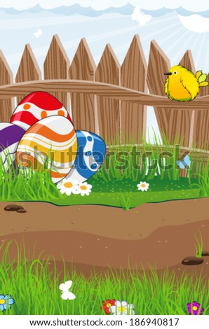 Bird and colorful Easter eggs near a wooden fence on a spring meadow