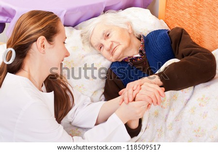 Young doctor holds the old woman's hands Young doctor holds the old woman's hands