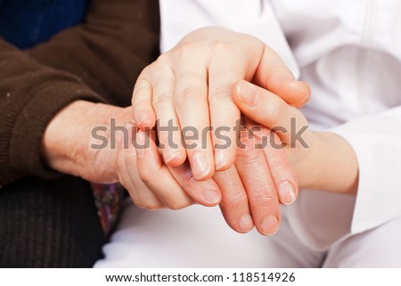 Young sweet doctor holds the old woman hands