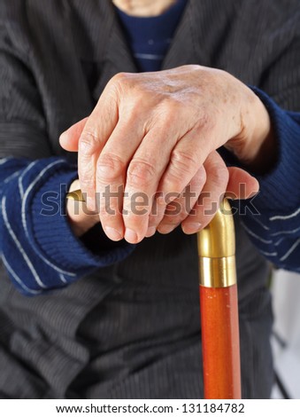 Elderly hands resting on the walking stick