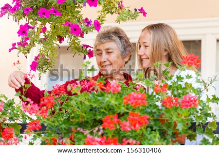 Elderly woman shows her flowers to her assistant
