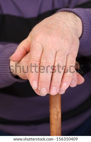 Old man\'s worker hand resting on the walking stick
