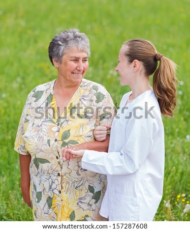 Elderly woman with her caretaker walking in the nature