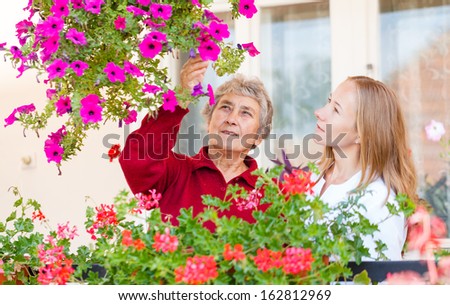 Elderly woman shows her flowers to her assistant