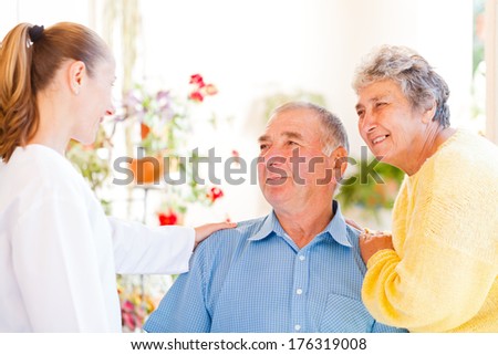 Happy Elderly Couple Talking With Their Carer
