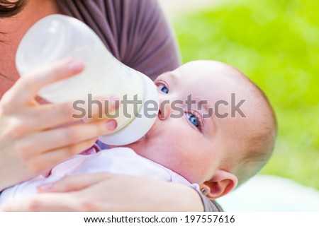 Young mother feeding her baby with milk bottle