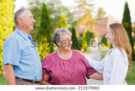 Happy elderly couple with their carer in the nature