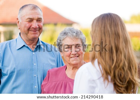 Happy elderly couple talking with their carer