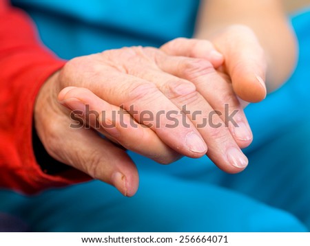 Young carer giving helping hands for elderly woman