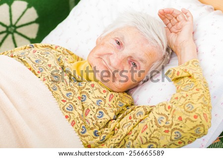 Sweet smiling elderly woman resting in bed