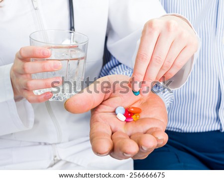 Young doctor helping the elderly man to take the pills