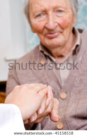 Young doctor holds old man\'s hand