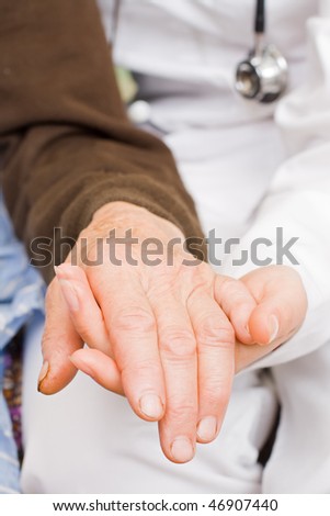 Young doctor holds old man\'s hand