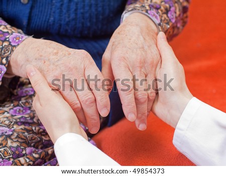 Young doctor holds the old woman's hand