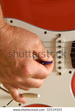 Closeup of right hand playing red electric guitar