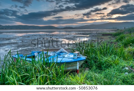 Old boat at lakeside at sunrise