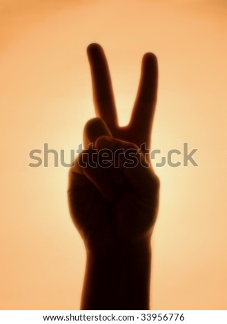Back-lit hand signaling \'peace\'