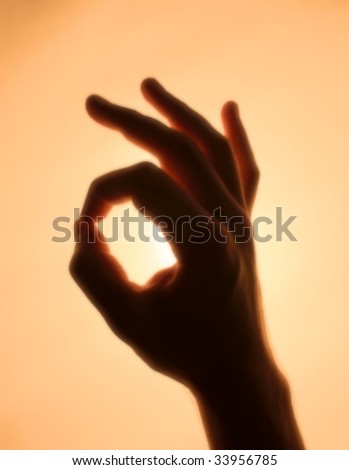 Back-lit hand signaling \'OK\'
