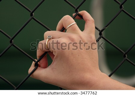 Young woman\'s hand gripping a fence