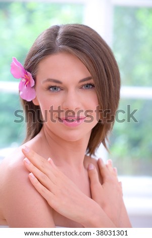 Portrait of beautiful naked girl in a spa with flower in her hair