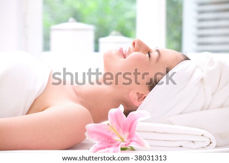 Young beautiful woman relaxing in spa - wellness with a flower lily
