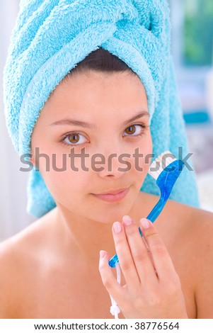Young girl cleaning face with peeling brush