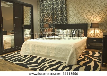 Interior of modern bedroom. Cosy walls with graphical elements. Mirrors and zebra carpet.