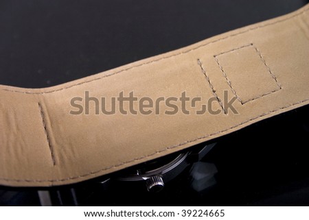 Closeup of leather watch strap on black background.