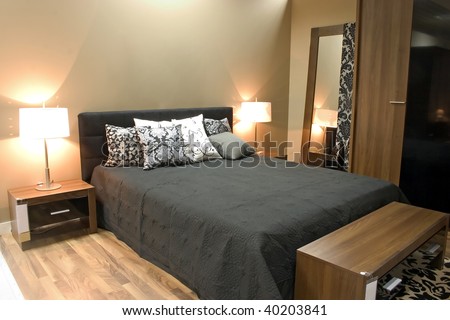 Interior of modern bedroom with furniture and mirrors in warm orange colors.