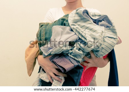 Woman holding a huge pile of clothes . Laundry, Clothing